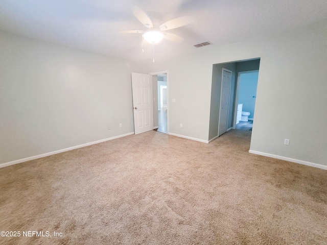 carpeted spare room with ceiling fan, visible vents, and baseboards