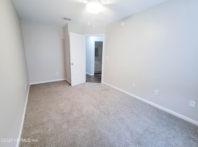 spare room featuring baseboards, visible vents, and carpet flooring