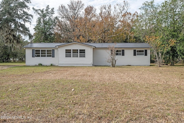 back of house featuring metal roof and a yard