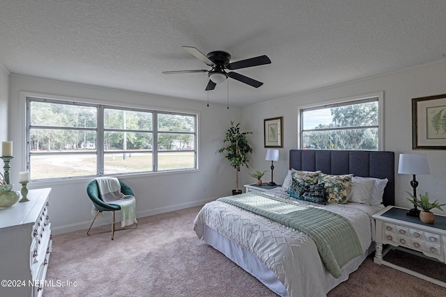 bedroom with a textured ceiling, baseboards, a ceiling fan, and light colored carpet