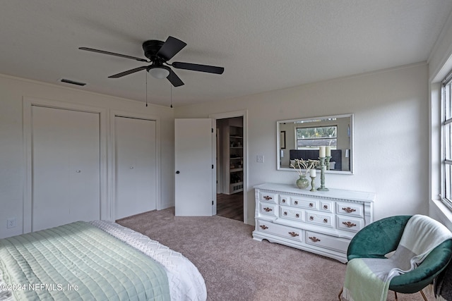 carpeted bedroom with a ceiling fan, visible vents, and a textured ceiling