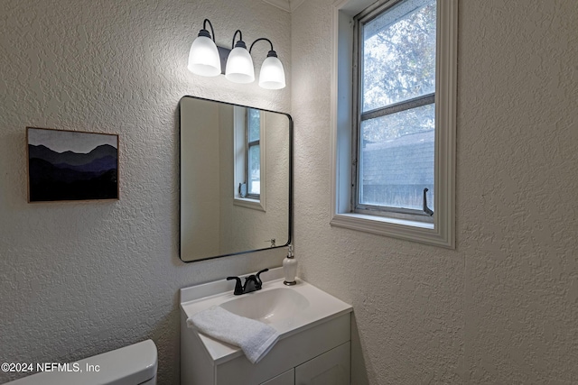 bathroom featuring a textured wall, vanity, and toilet