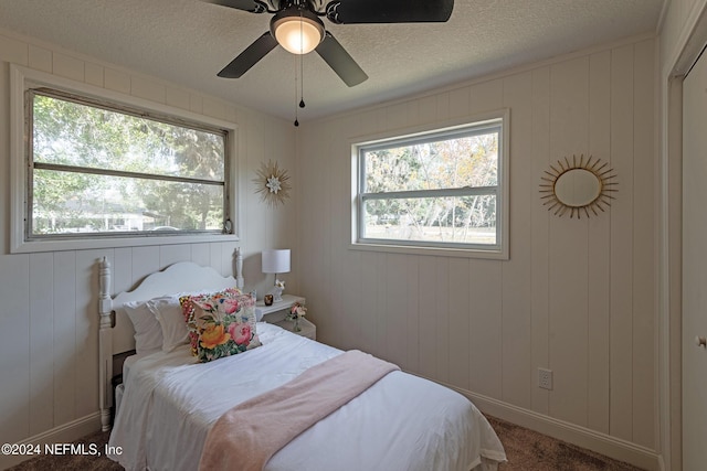 bedroom featuring carpet floors, multiple windows, ceiling fan, and a textured ceiling