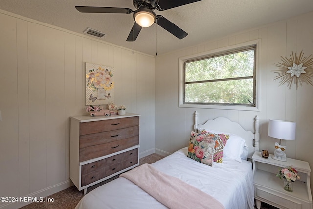 bedroom with a textured ceiling, ceiling fan, carpet flooring, and visible vents