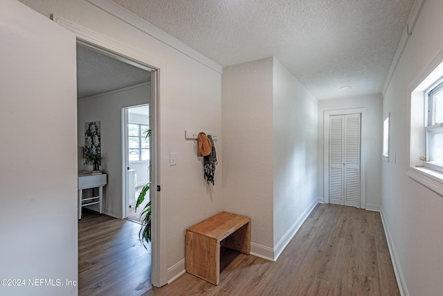 hall with a textured ceiling, wood finished floors, and baseboards