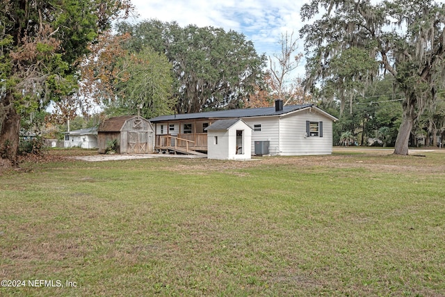 rear view of house with a storage shed, a lawn, a chimney, cooling unit, and an outdoor structure