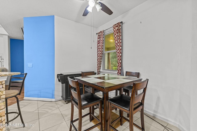 dining space with ceiling fan, light tile patterned flooring, and baseboards