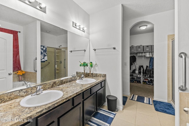 full bathroom featuring a stall shower, a sink, and tile patterned floors