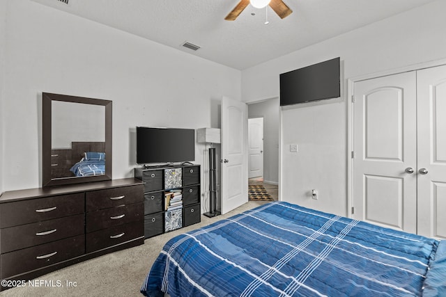 bedroom featuring light carpet, visible vents, ceiling fan, a textured ceiling, and a closet