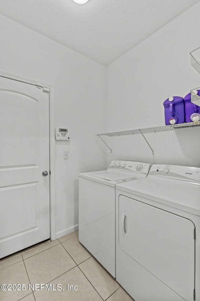 washroom featuring laundry area, light tile patterned floors, baseboards, and separate washer and dryer