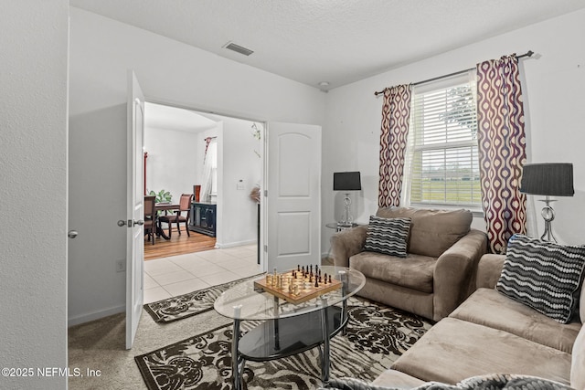 living area featuring visible vents, a textured ceiling, baseboards, and light tile patterned flooring