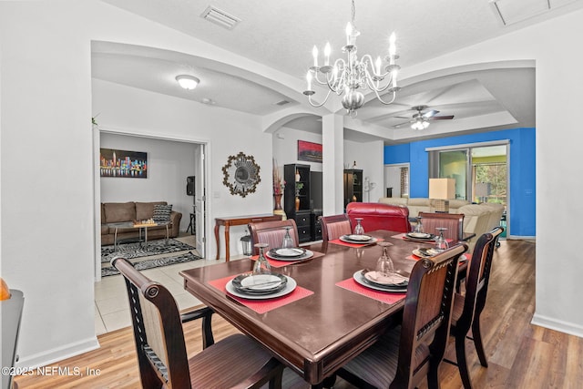 dining room featuring arched walkways, ceiling fan with notable chandelier, visible vents, and light wood-style floors