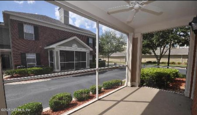 unfurnished sunroom featuring a ceiling fan and a fireplace