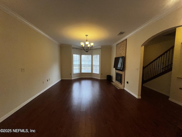 unfurnished living room featuring visible vents, dark wood-type flooring, a glass covered fireplace, ornamental molding, and a chandelier