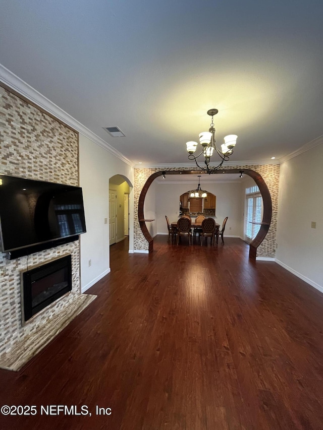 unfurnished dining area with arched walkways, a tile fireplace, wood finished floors, visible vents, and crown molding