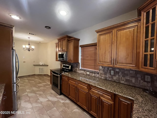 kitchen featuring visible vents, glass insert cabinets, appliances with stainless steel finishes, brown cabinets, and backsplash