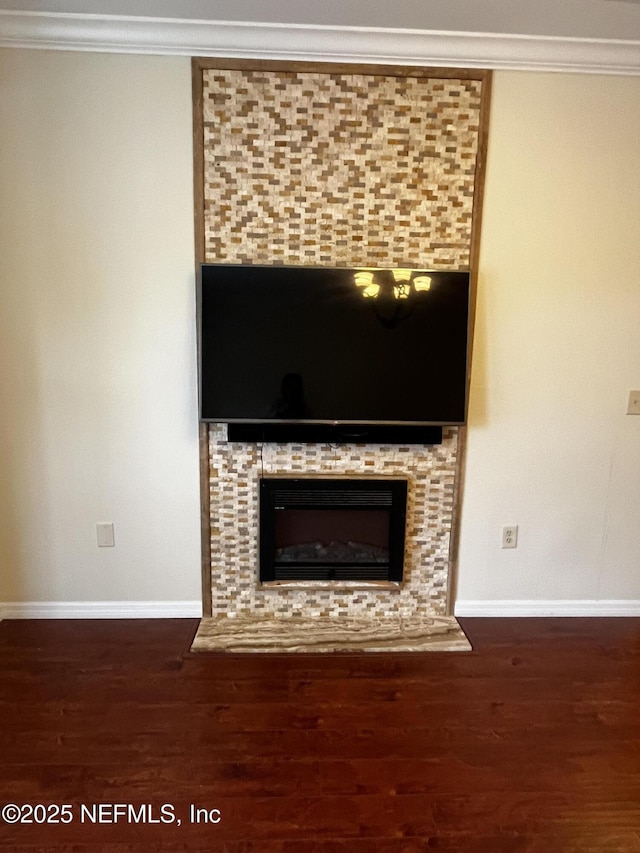 interior details featuring ornamental molding, a fireplace, baseboards, and wood finished floors