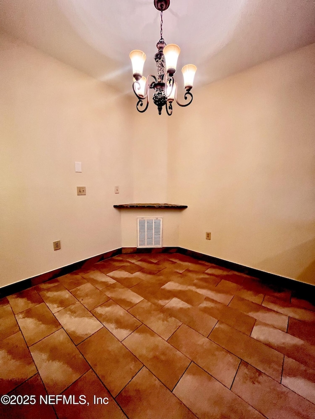 spare room featuring tile patterned flooring, baseboards, visible vents, and a notable chandelier