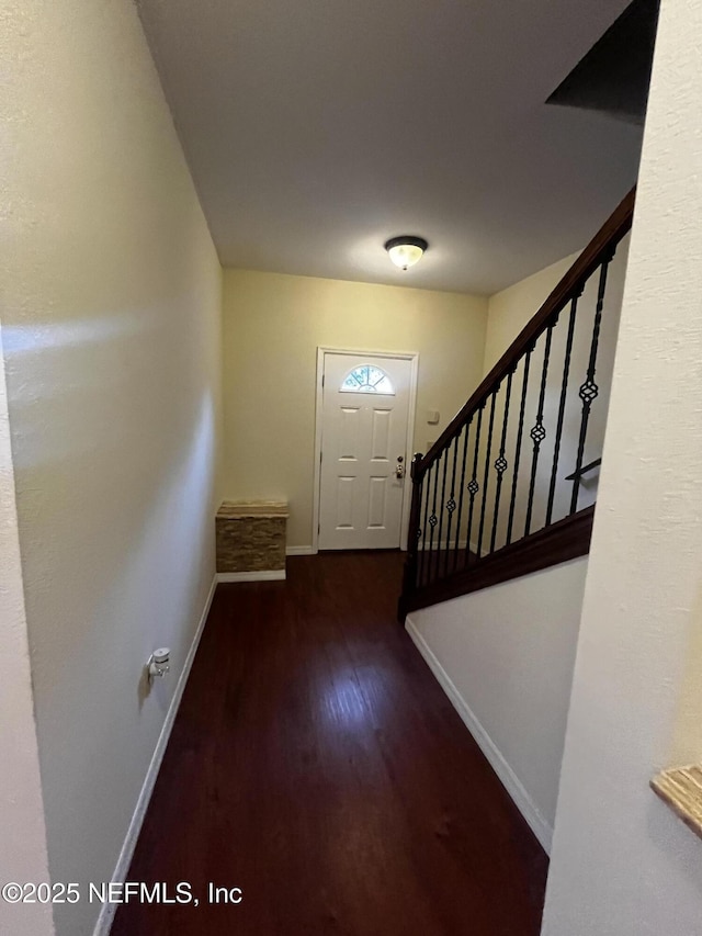 doorway featuring stairs, baseboards, and wood finished floors