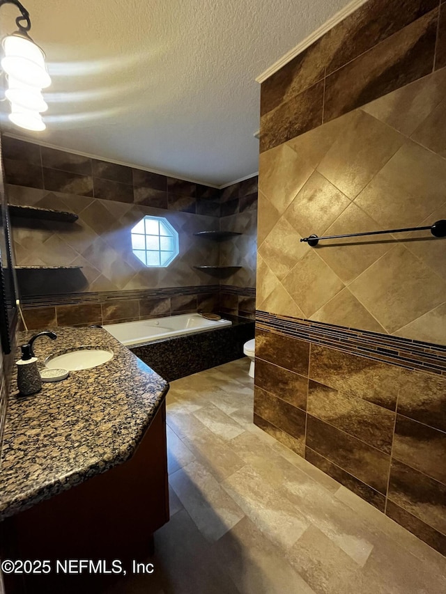 full bath with a textured ceiling, toilet, vanity, tile walls, and a bathtub