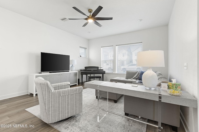 office area featuring a ceiling fan, visible vents, baseboards, and wood finished floors