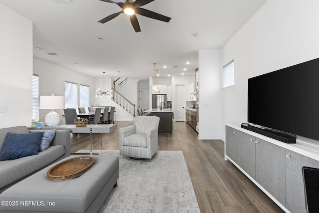 living room with dark wood-style floors, recessed lighting, baseboards, and ceiling fan with notable chandelier