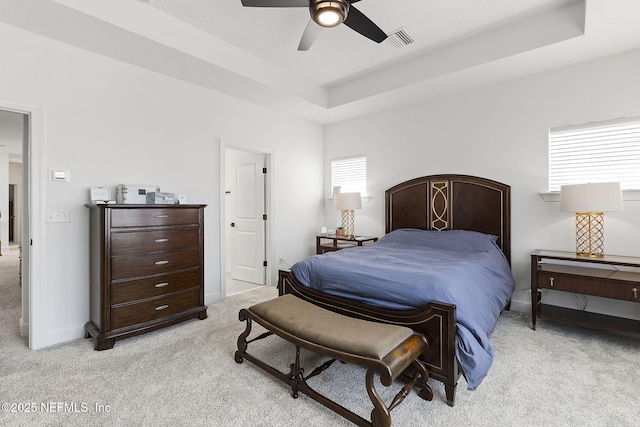 bedroom featuring light carpet, multiple windows, a raised ceiling, and visible vents