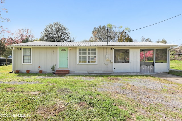 view of front of property featuring entry steps, metal roof, a front yard, and a sunroom