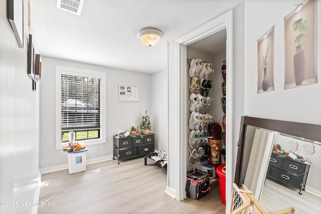 interior space featuring light wood finished floors, baseboards, visible vents, and a textured ceiling