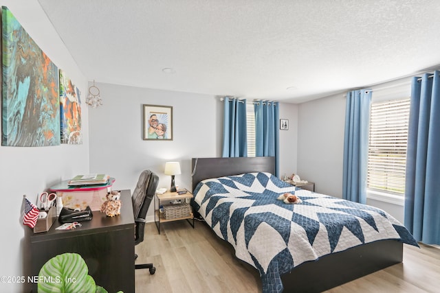 bedroom with light wood-style floors and a textured ceiling