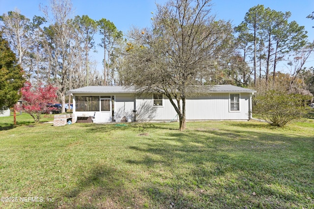 rear view of property featuring a sunroom, metal roof, and a lawn