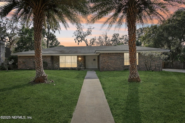 view of front of property featuring brick siding and a yard