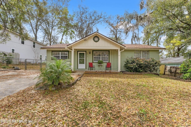 ranch-style home featuring a front lawn, fence, a porch, and board and batten siding