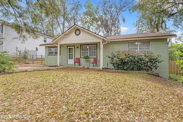 single story home featuring covered porch, fence, and a front yard