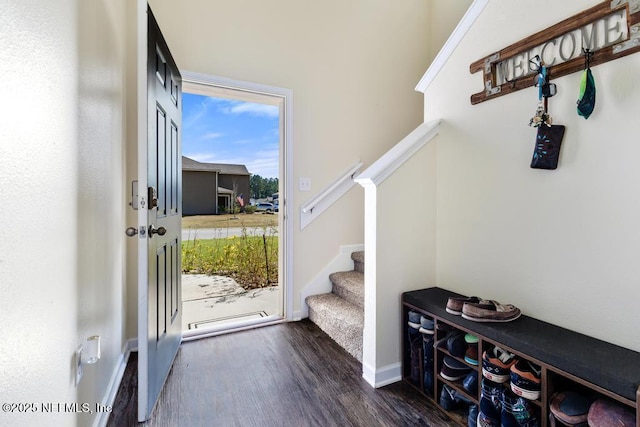 doorway to outside featuring dark wood finished floors, baseboards, and stairs