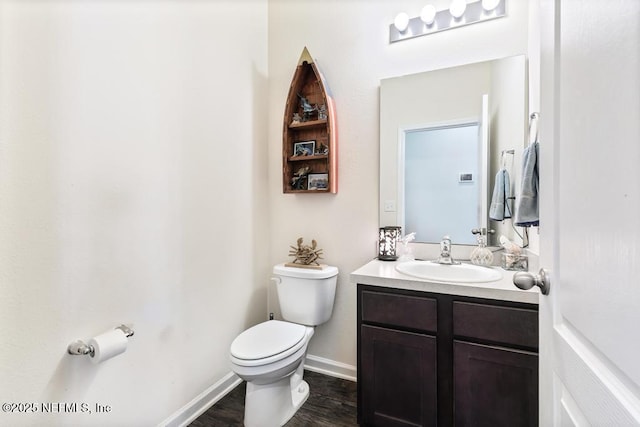 bathroom with wood finished floors, vanity, toilet, and baseboards