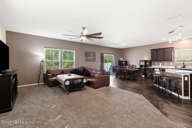 living room featuring baseboards, visible vents, a ceiling fan, and a healthy amount of sunlight