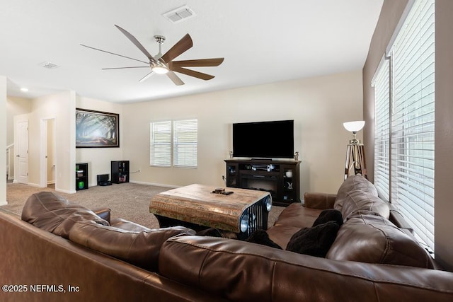 living room with carpet flooring, ceiling fan, visible vents, and baseboards