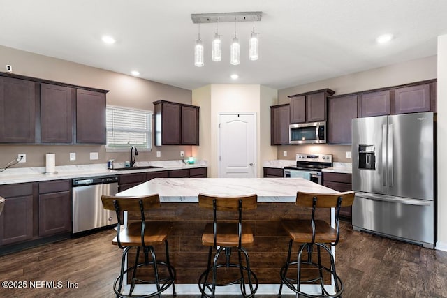 kitchen with stainless steel appliances, dark brown cabinets, dark wood-style flooring, and a sink