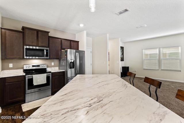 kitchen featuring light stone counters, visible vents, appliances with stainless steel finishes, dark brown cabinets, and baseboards