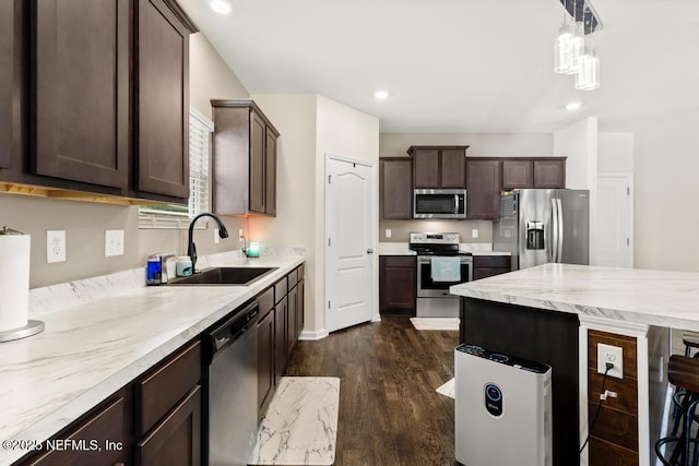 kitchen featuring dark wood finished floors, light countertops, appliances with stainless steel finishes, a sink, and dark brown cabinetry