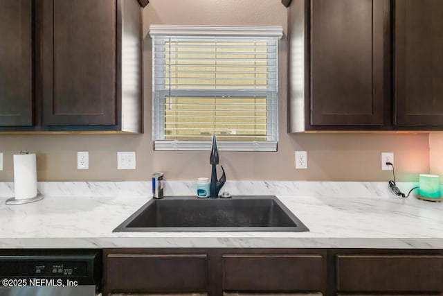 kitchen featuring dishwasher, dark brown cabinets, light stone counters, and a sink