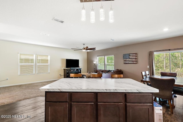 kitchen with open floor plan, light countertops, hanging light fixtures, and visible vents