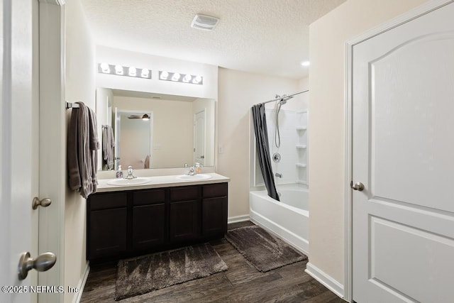 bathroom with double vanity, shower / bath combo with shower curtain, a sink, a textured ceiling, and wood finished floors