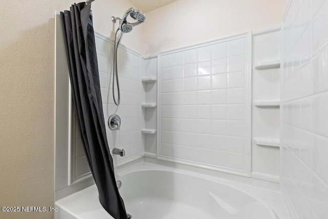 bathroom with a textured wall and shower / tub combo