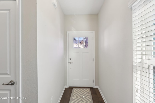 doorway with dark wood-type flooring and baseboards