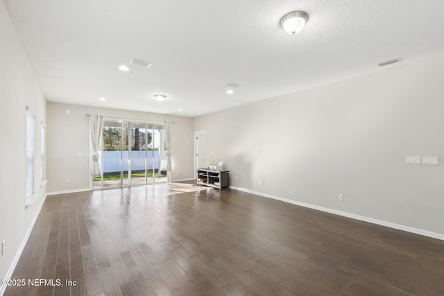 spare room with recessed lighting, dark wood finished floors, visible vents, and baseboards