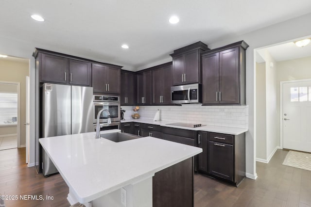 kitchen featuring a sink, light countertops, appliances with stainless steel finishes, dark brown cabinets, and backsplash