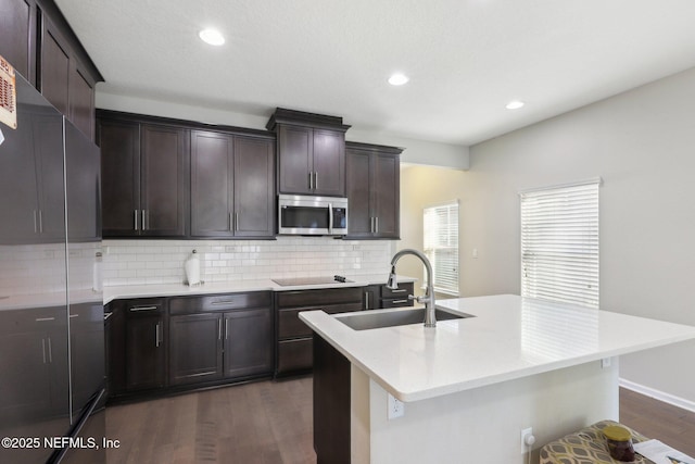 kitchen with a sink, light countertops, appliances with stainless steel finishes, tasteful backsplash, and dark wood finished floors