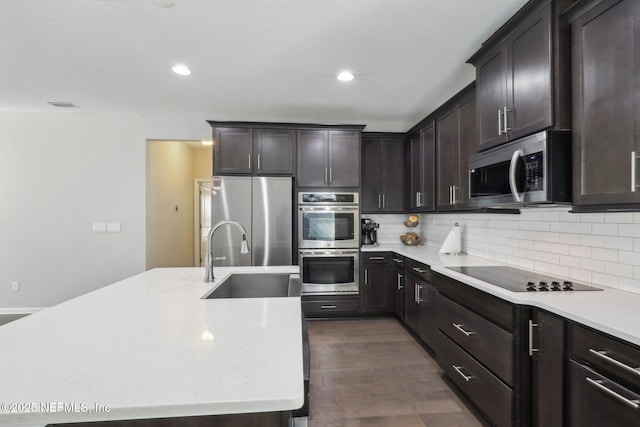 kitchen featuring visible vents, decorative backsplash, appliances with stainless steel finishes, dark wood-style flooring, and a sink